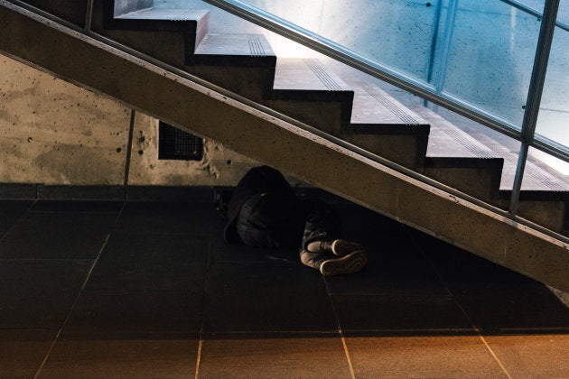 A man sleeping under the stairs at Square Victoria metro station, Montreal, Que.