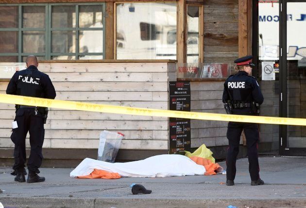 Police secure an area around a covered body in Toronto after a van mounted a sidewalk crashing into a number of pedestrians on April 23, 2018.