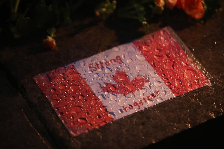 A Canadian flag labelled "Strong Together" is seen during a candlelight vigil at Olive Square near the corner of Yonge Street and Finch Avenue for victims of a van rampage that killed 10 and injured 14.
