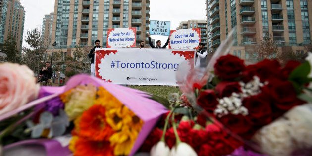 A local Toronto Muslim group holds up signs for love and courage for victims of the April 23 crash, at a memorial on Yonge Street at Finch Avenue on April 24, 2018 in Toronto.