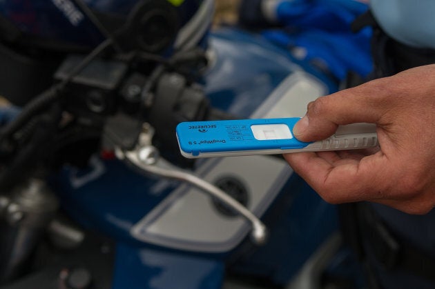 A foreign police officer shows off a positive THC saliva test (used to detect cannabis use).