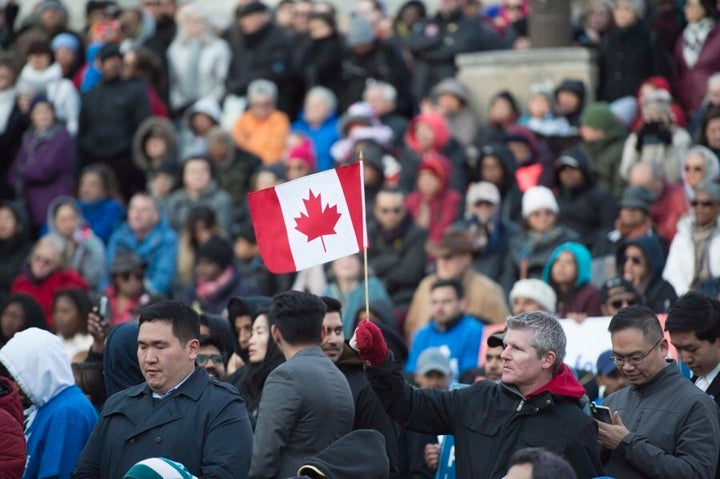 A man holds a Canadian flag at a vigil remembering the victims of Monday's deadly van attack, at Mel Lastman Square in Toronto on April 29, 2018.
