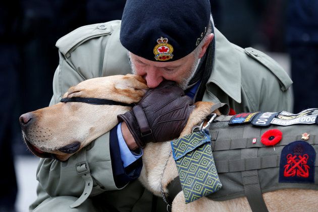 A veteran embraces his service dog during Remembrance Day ceremonies at the National War Memorial in Ottawa on Nov. 11, 2016.