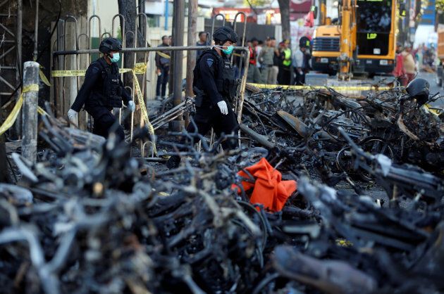 Members of the Indonesian Special Forces Police counter-terrorism squad walk by burned motorcycles following a blast at the Pentecost Church Central Surabaya, in Surabaya, Indonesia on May 13, 2018.
