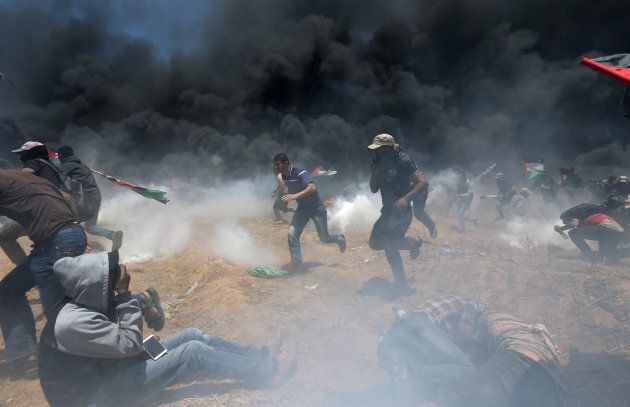 Palestinian demonstrators run for cover from Israeli fire and tear gas during a protest against U.S. embassy move to Jerusalem and ahead of the 70th anniversary of Nakba, at the Israel-Gaza border in the southern Gaza Strip on May 14, 2018.