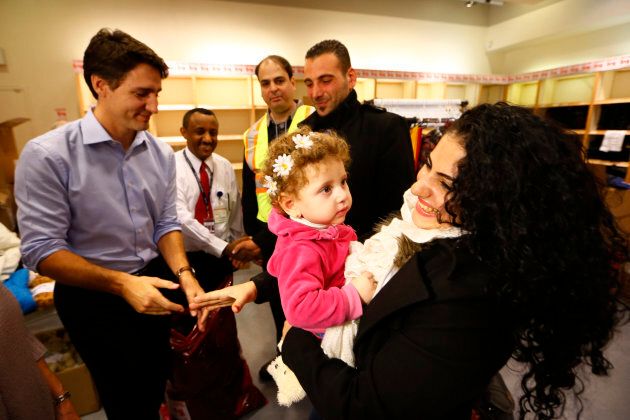 Syrian refugees are greeted by Prime Minister Justin Trudeau (L) on their arrival from Beirut at the Toronto Pearson International Airport Dec. 11, 2015.