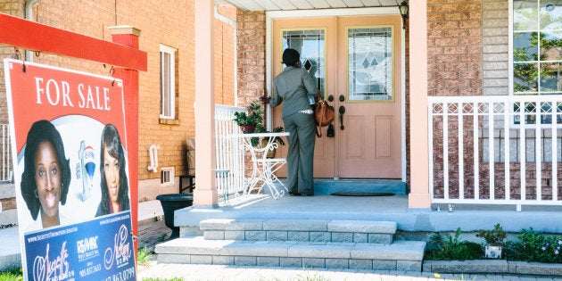 A real estate agent stands outside of a home holding an open house in Brampton, Ont., near Toronto, Sat. May 20, 2017. The number of new listings of homes for sale in Greater Toronto has taken a deep drop as sellers wait out the market slump.