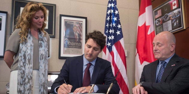 Sophie Gregoire Trudeau and the former ambassador of the United States to Canada Bruce Heyman look on as Prime Minister Justin Trudeau signs a book of condolence at the United States embassy in Ottawa on June 14, 2016.