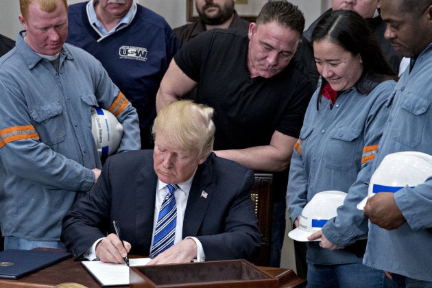 U.S. President Donald Trump signs a proclamation on adjusting imports of steel into the United States next to steel and aluminum workers in the Roosevelt Room of the White House in Washington, D.C., on March 8, 2018.