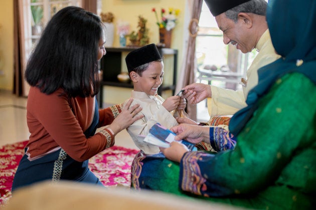 A boy is presented with a gift of money from his grandparents as part of the Islamic celebration of Eid al-Fitr in Malaysia.