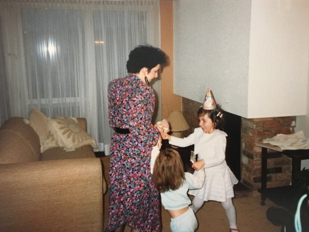 The author, in a birthday hat, dancing with her mother and younger sister in their spectacularly 80s-beige living room.