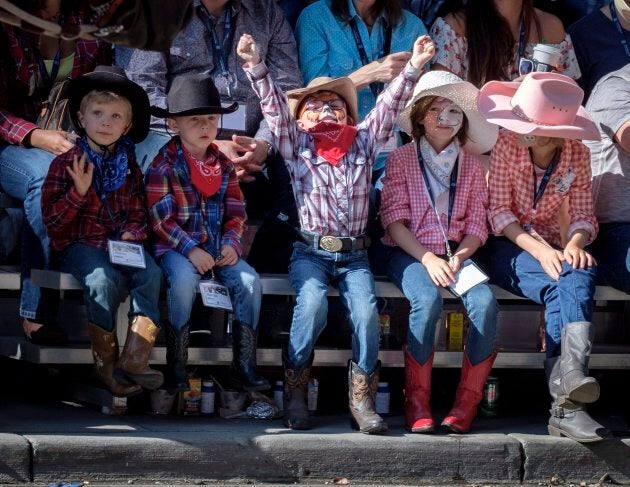 Young spectators cheer during the Calgary Stampede parade on July 6, 2018.