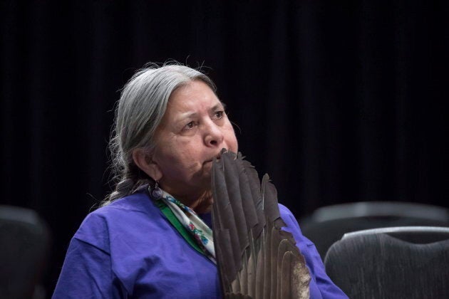 A woman holds a eagle feather as she listens to Anni Phillips give her testimony during the National Inquiry of Missing and Murdered Indigenous Women and Girls in Richmond, B.C. on April 4, 2018.