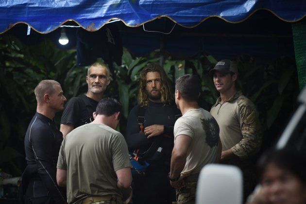 A group of foreign divers and U.S. soldiers, wearing light-coloured shirts, gather at the Tham Luang cave area during rescue operations on July 6, 2018.