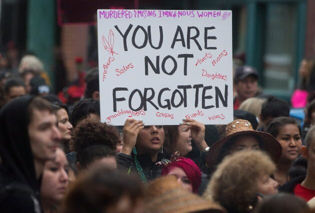 A woman holds a sign as hundreds of people march through the Downtown Eastside during the 25th annual Women's Memorial March in Vancouver, B.C., on Feb. 14, 2015.