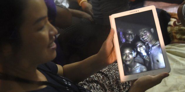 A happy family member shows the latest pictures of the missing boys taken by rescue divers inside Tham Luang cave on July 2, 2018.
