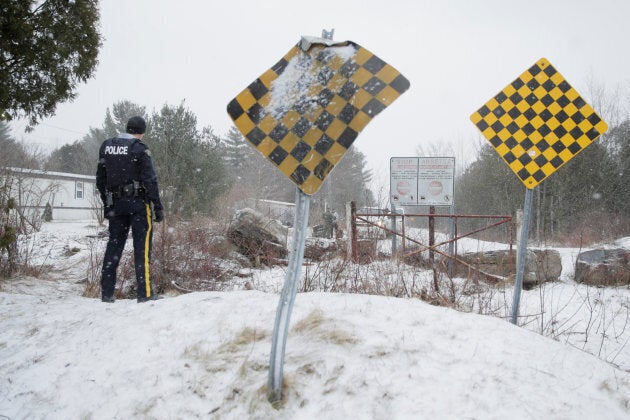 An RCMP officer watches as a man is checked by U.S. border patrol before he crossed the U.S.-Canada border into Hemmingford, Que. on March 2, 2017.