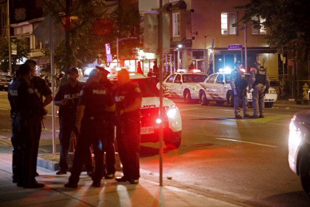 Toronto police officers walk the scene at Danforth Avenue on July 23, 2018.