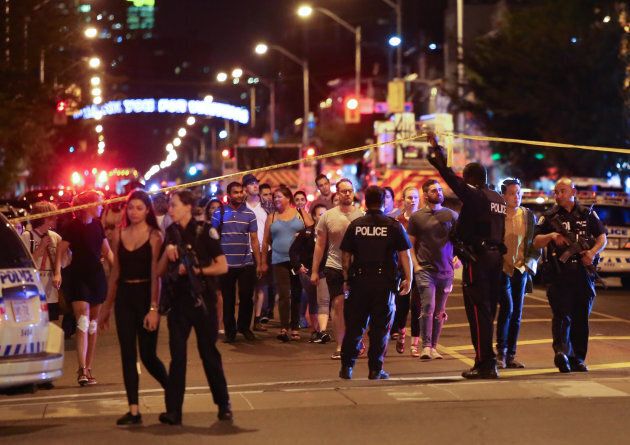 People leave an area taped off by the police near the scene of a mass shooting in Toronto on July 22, 2018.