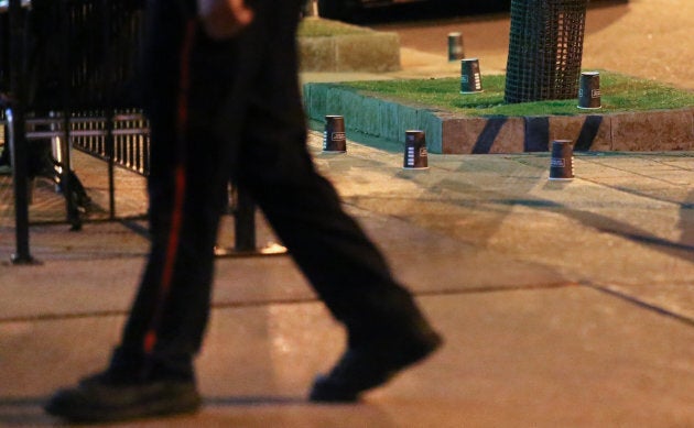 A police officer walks past evidence marked with coffee cups after a mass shooting in Toronto on July 23, 2018.