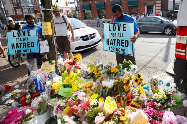 Shaheer Danial of the Ahmadiyya Muslim Community holds a sign at a makeshift memorial on Danforth Avenue.