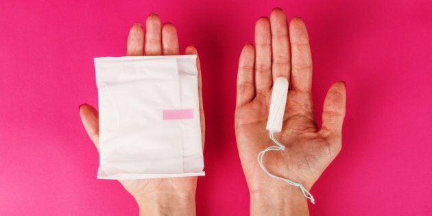 Woman holding menstrual tampon and pad.