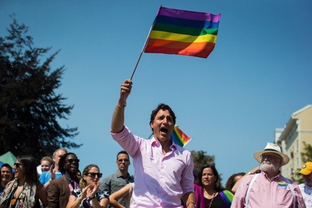 Justin Trudeau waves a rainbow flag while marching in the Pride Parade in Vancouver on Aug. 5, 2018.