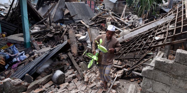 A man carries a small bicycle through the ruins of houses damaged by an earthquake in West Lombok, Indonesia on Monday in this photo taken by Antara Foto.