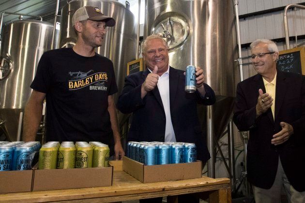 Ontario Premier Doug Ford and Finance Minister Vic Fedeli stack beer with Barley Days employee Kyle Baldwin before announcing the buck-a-beer plan at Barley Days brewery in Picton, Ont. on Aug. 7, 2018.