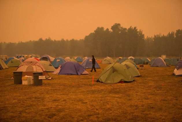 A man walks between tents at a camp where wildfire firefighters and staff are staying at an outdoor sports field, in Fraser Lake, B.C., on Aug. 22, 2018.