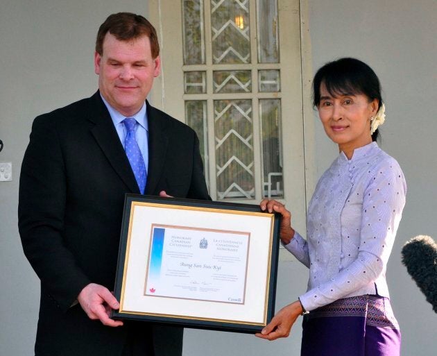 Former Canadian foreign affairs minister John Baird, left, presents an honorary Canadian citizenship certificate to Myanmar's democracy leader Aung San Suu Kyi during a press briefing after their meeting at her home on March 8, 2012, in Yangon, Myanmar.