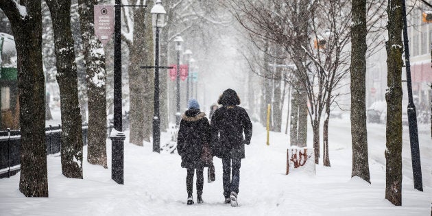 People walk down a street as large amounts of snow falls in Toronto, Dec. 11, 2014.