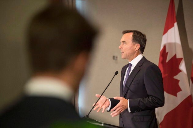 An aide looks on as federal Finance Minister Bill Morneau addresses journalists in Toronto on Aug. 30, 2018 about the government's Trans Mountain pipeline plan.