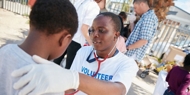 Shot of a volunteer doctor examining a young patient with a stethoscope.