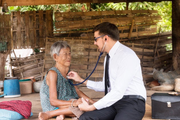 Doctor listening to a patient's heart beat and breathing in a rural area.