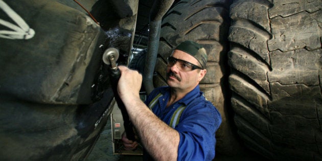 CANADA - MARCH 10: Jessy Martell, a worker at Kal Tire, located north of Fort McMurray, Alberta, Canada near the Syncrude Mildred Lake facility, patches a damaged area of a tire for a Caterpillar 797 dump truck Monday, March 8, 2006. The Caterpillar 797 is the world's largest mining dump truck and is used extensively during mining operations at the nearby Syncrude oil sands complex. (Photo by Norm Betts/Bloomberg via Getty Images)