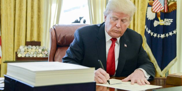 U.S. President Donald Trump signs a tax-overhaul bill into law in the Oval Office of the White House in Washington, D.C., Fri. Dec. 22, 2017.
