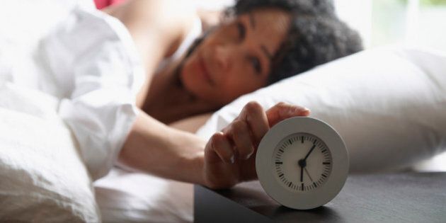 Black woman turning of alarm clock