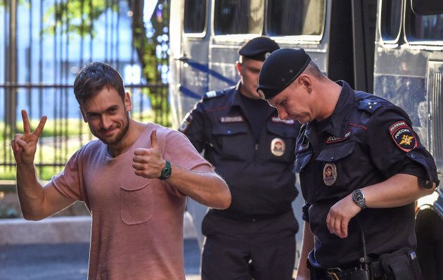 Pyotr Verzilov gestures as he walks with police during a court hearing at a courthouse in Moscow, on July 31, 2018.