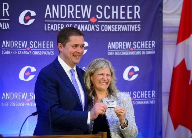 New Conservative MP Leona Alleslev is presented with a party card by Conservative Leader Andrew Scheer as she is welcomed during the caucus meeting on Parliament Hill in Ottawa on Sept. 19, 2018.