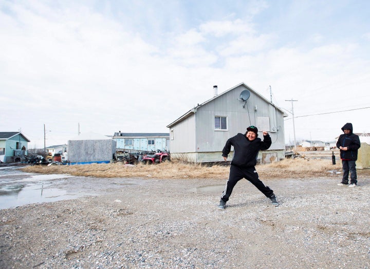 Teenage boys throw rocks in the northern Ontario First Nations reserve in Attawapiskat, Ont., on April 16, 2016.