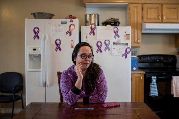 Desiree Wolfrey sits in the common kitchen of the community's women's shelter, adorned with purple domestic violence awareness ribbons.