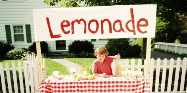Boy (6-8) selling lemonade from sidewalk stand