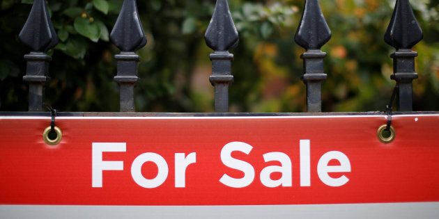 A real estate sign is seen hanging on a fence in front of a house for sale in Ottawa, Aug. 15, 2017.