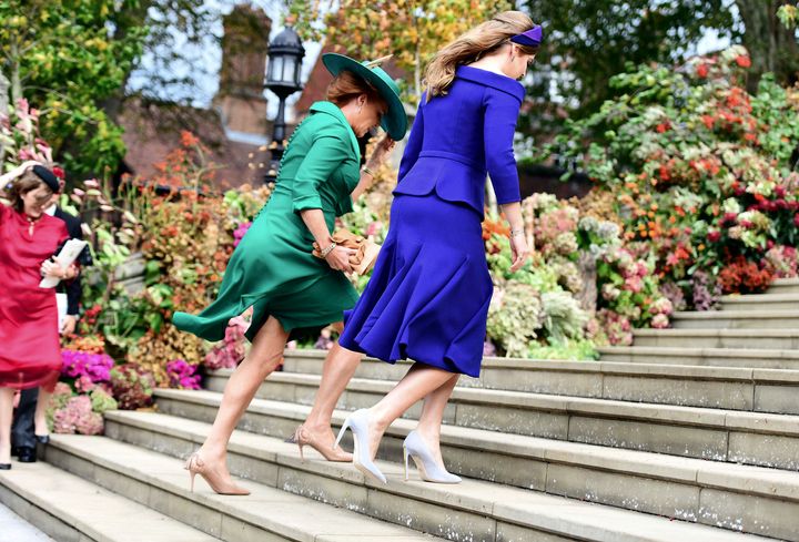 Britain's Princess Beatrice, right, and her mother, Sarah Ferguson, left, battle the gusty winds up the stairs to the chapel.