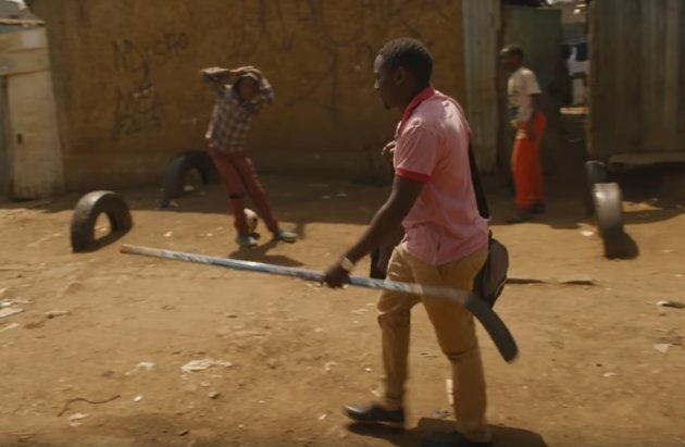 A member of the Kenya Ice Lions walks through the streets of Nairobi with a hockey stick.