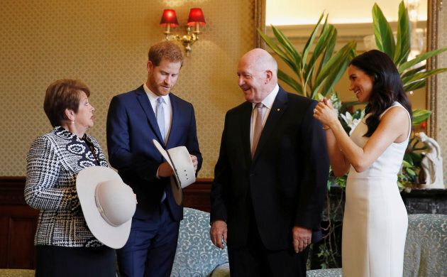 Prince Harry and Meghan, Duchess of Sussex react as they receives traditional Australian hats from Australia's Governor General Sir Peter Cosgrove and his wife Lady Cosgrove.