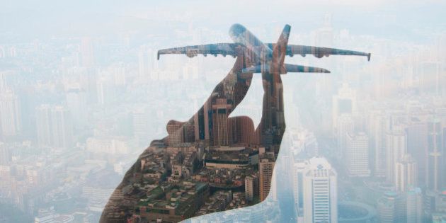 double exposure of mans hand holding a toy plane and cityscape in the background