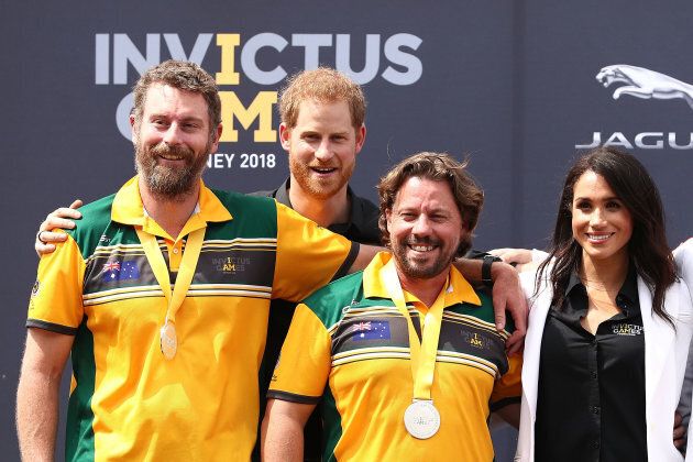 Harry and Meghan pose with Silver medallists Craig McGrath and Scott Reynolds of Australia during the medal ceremony during the JLR Drive Day at Cockatoo Island on Saturday.