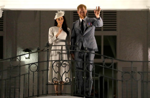 Harry and Meghan wave from a balcony as they arrive for an official dinner at the Grand Pacific Hotel on Tuesday.